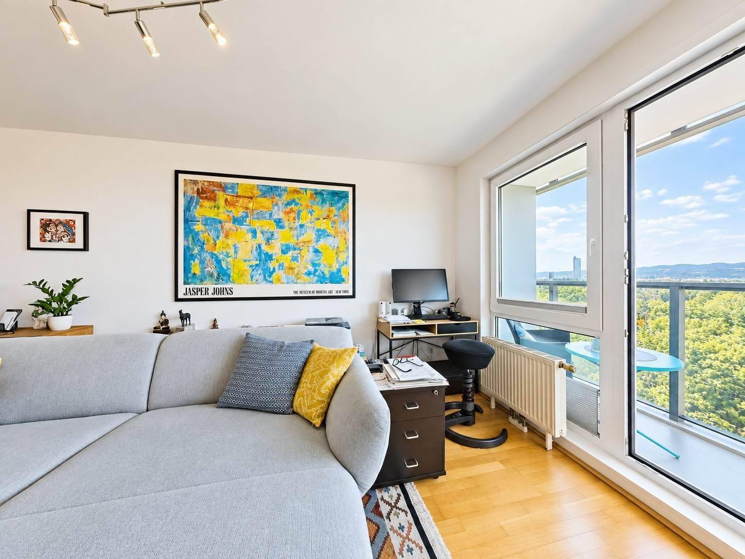 Wohnbereich mit bequemem Sofa, Arbeitsplatz und Zugang zu einem Balkon mit Weitblick.