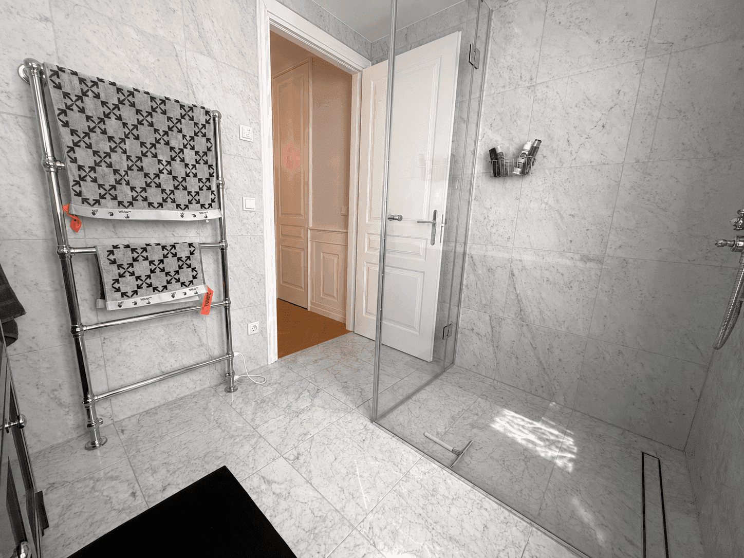 Elegantes Badezimmer mit Marmorfliesen, geräumiger begehbarer Dusche und beheiztem Handtuchhalter.