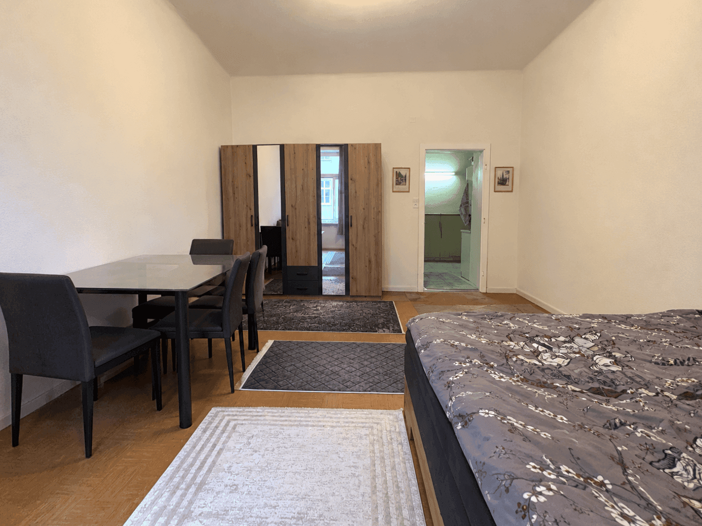 Schlafzimmer mit Essbereich, großem Kleiderschrank und Blick auf den angrenzenden Raum.