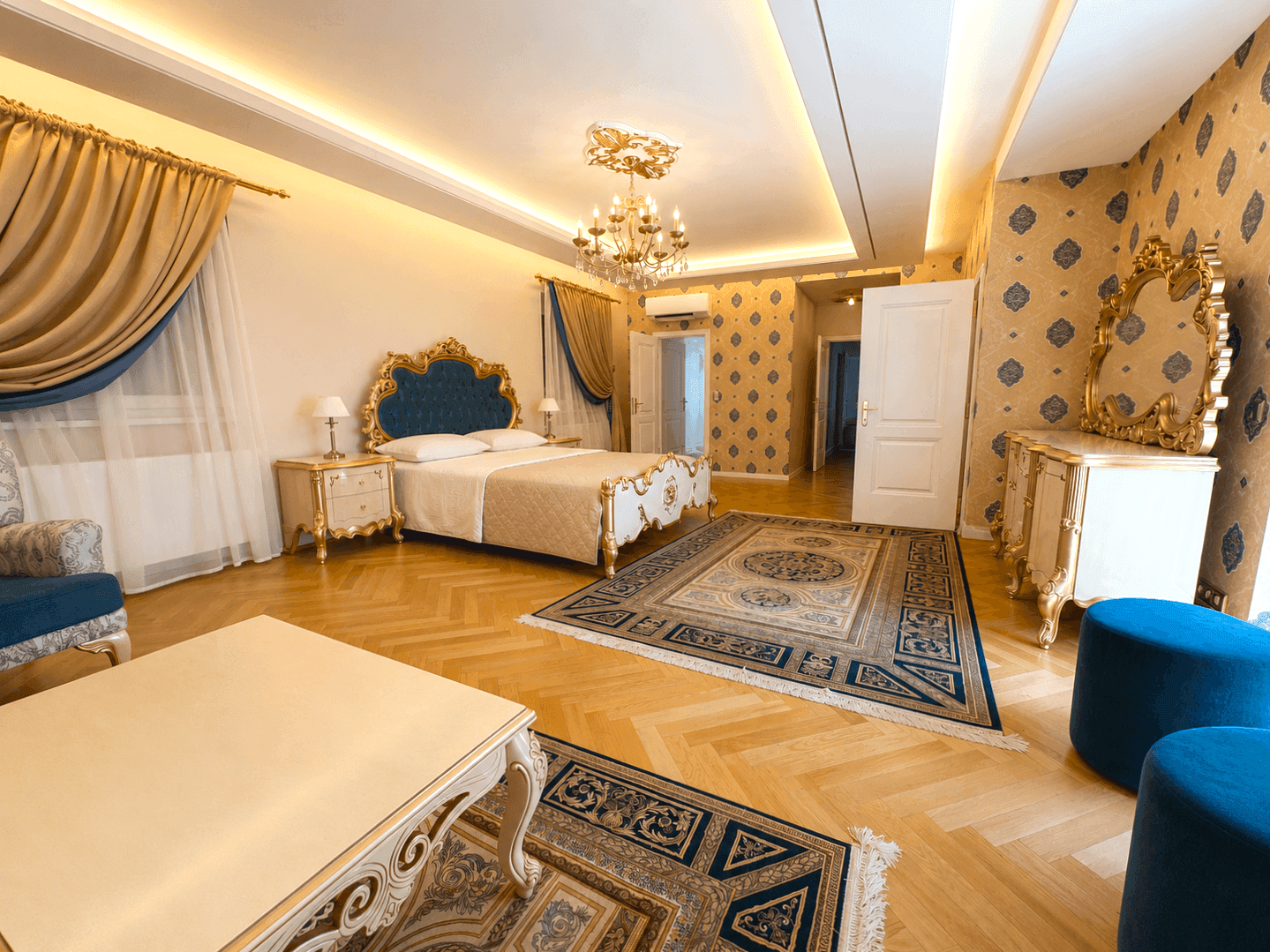 Helles Schlafzimmer mit luxuriöser Ausstattung, bequemen Sitzgelegenheiten und elegantem Parkettboden, ideal zum Entspannen.