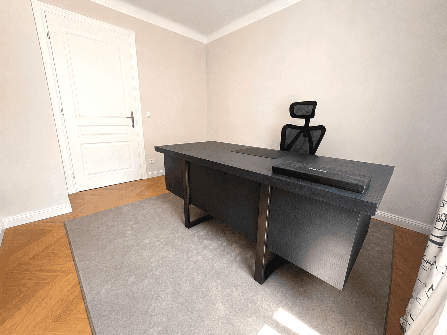 Ruhiges Arbeitszimmer mit großem dunklem Schreibtisch, Bürostuhl und hellem Fischgrätparkett.