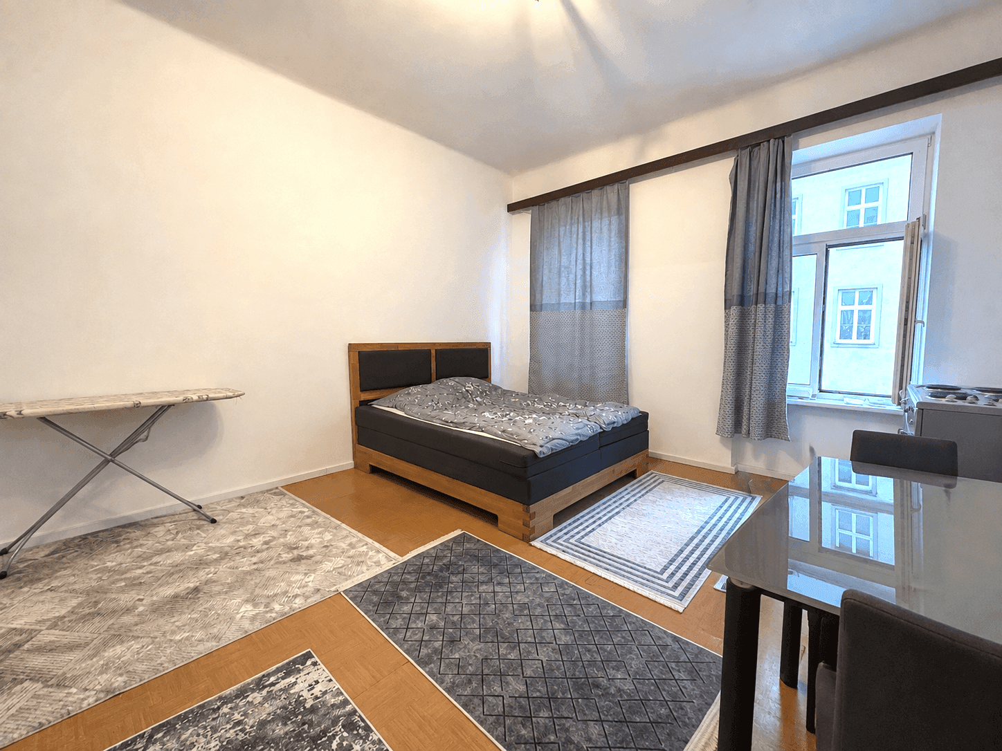 Geräumiges Schlafzimmer mit Holzboden, Doppelbett und einem kleinen Essbereich, gut beleuchtet.