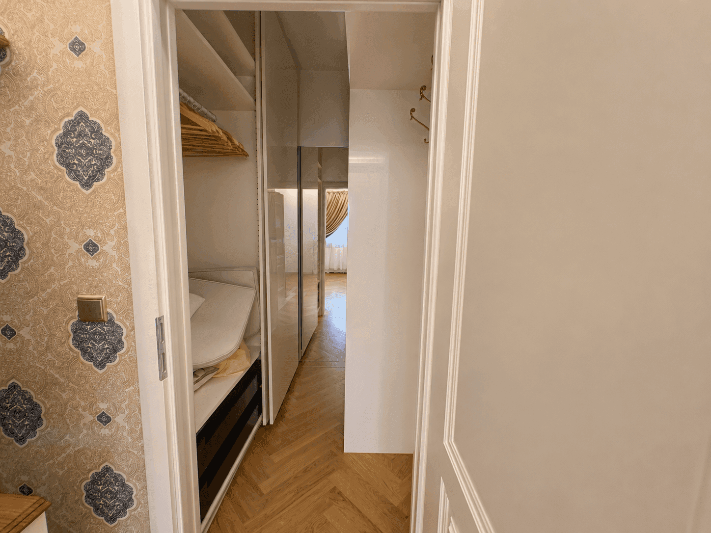 Praktischer begehbarer Kleiderschrank mit maßgefertigten Regalen und viel Stauraum, direkt vom Schlafzimmer aus zugänglich.
