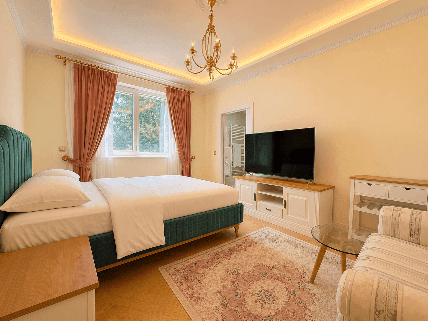 Helles Schlafzimmer mit grünem Polsterbett, Fernseher und großem Fenster, das viel Tageslicht hereinlässt.