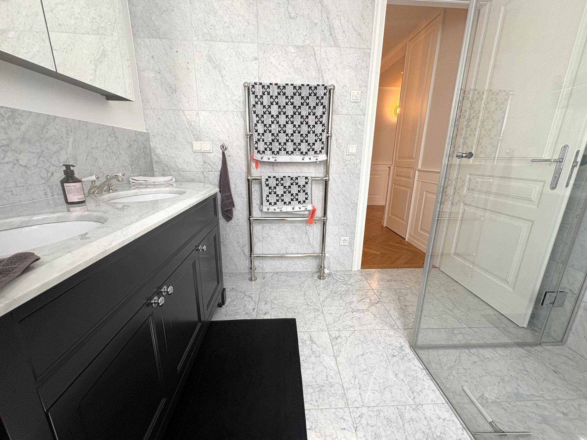 Stilvolles Badezimmer mit Doppelwaschtisch, beheiztem Handtuchhalter und begehbarer Dusche.