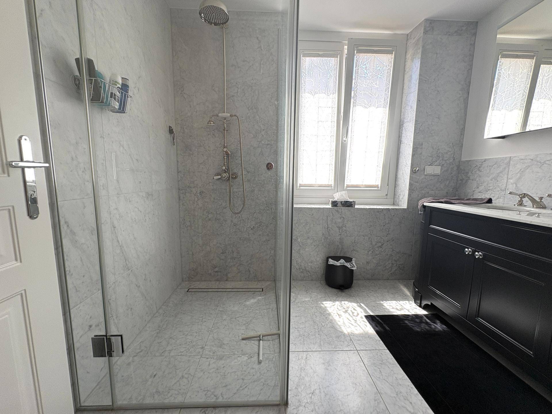 Helles Badezimmer mit begehbarer Dusche, Doppelwaschtisch und Fenster für natürliches Licht.