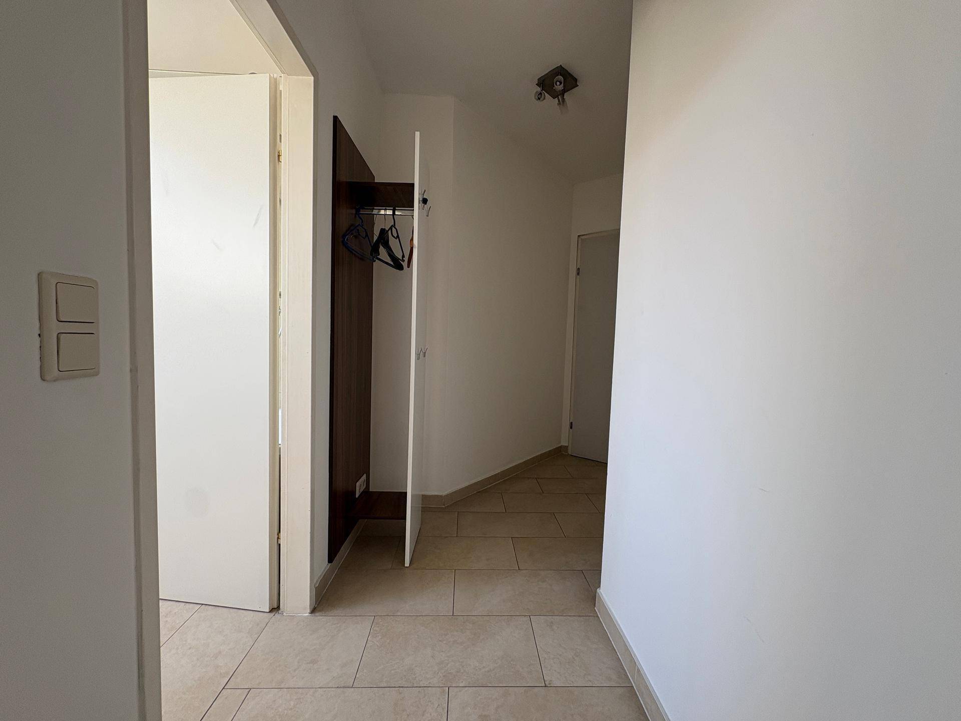 Geräumiger Flur mit Fliesenboden und integriertem Garderobenschrank, bietet praktischen Stauraum.
