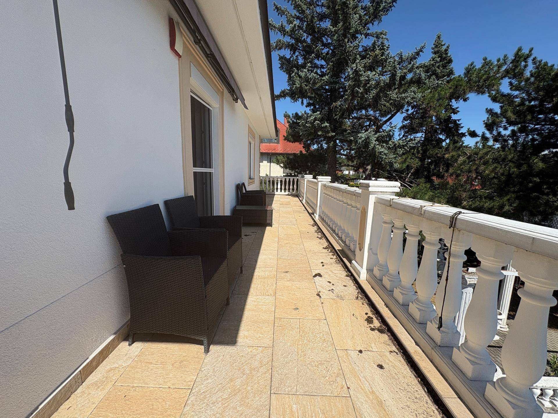 Langer Balkon mit Fliesenboden, klassischer Balustrade und bequemen Sitzgelegenheiten, um die Aussicht zu genießen.