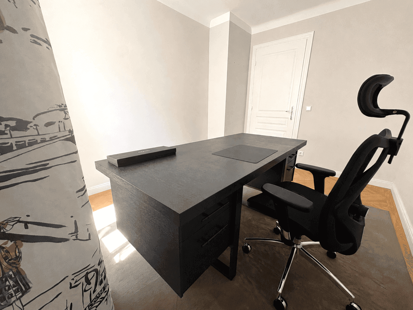 Funktionales Arbeitszimmer mit dunklem Schreibtisch, ergonomischem Stuhl und hellem Fischgrätparkett.
