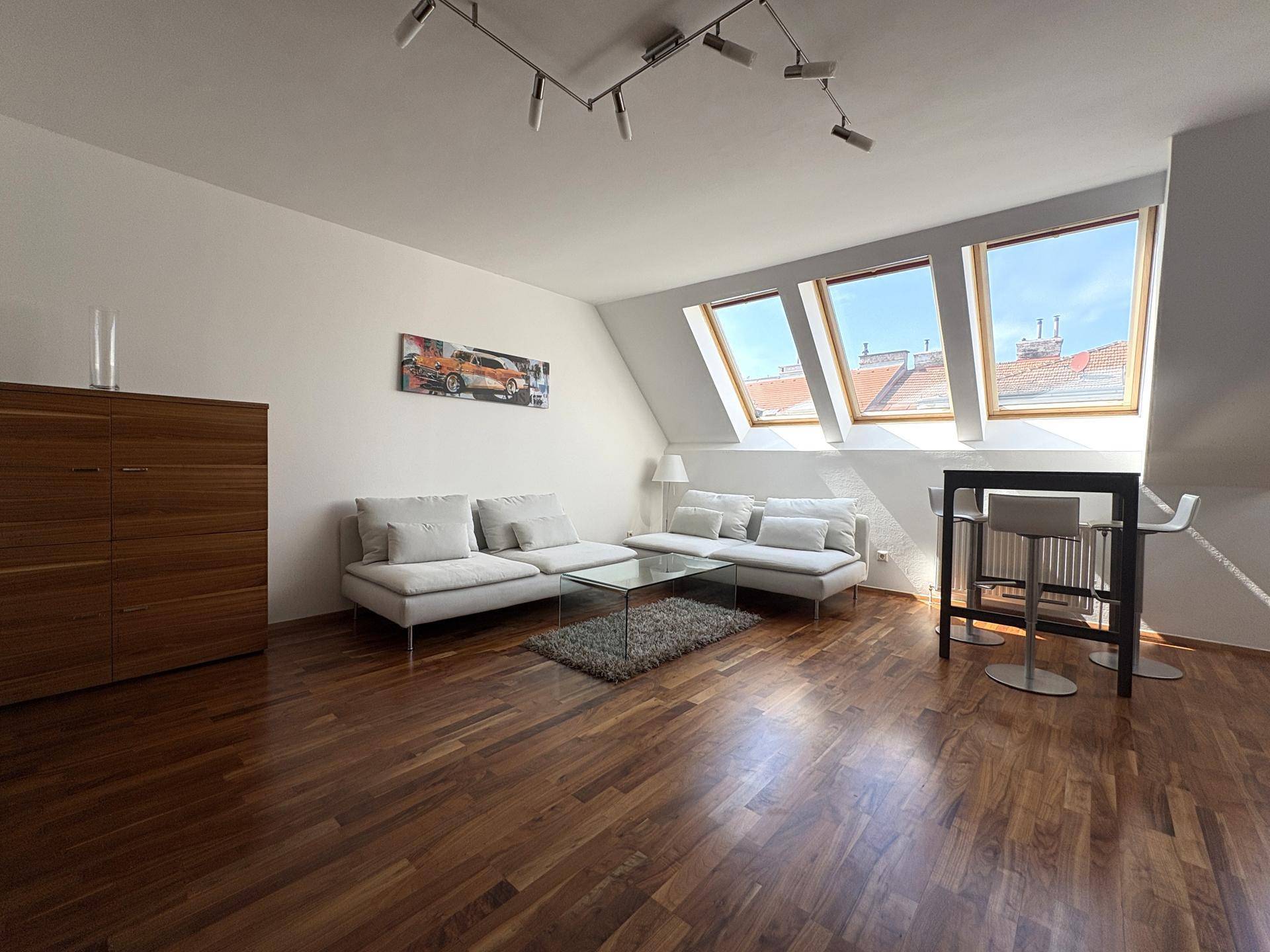 Geräumiger Wohnbereich mit dunklem Holzboden, bequemen Sofas und großen Dachfenstern für viel Licht.