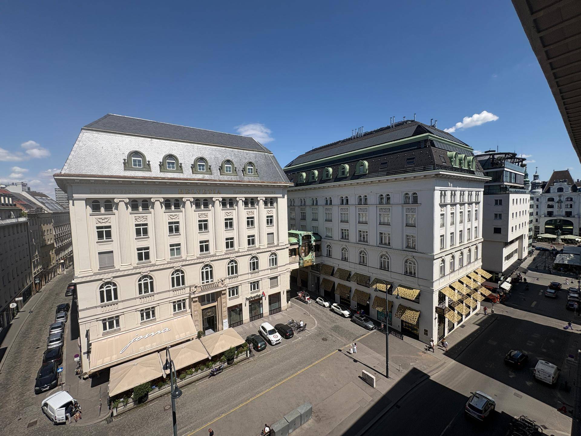 Weitläufiger Blick über eine historische Stadtstraße mit eleganten Gebäudefassaden unter blauem Himmel.