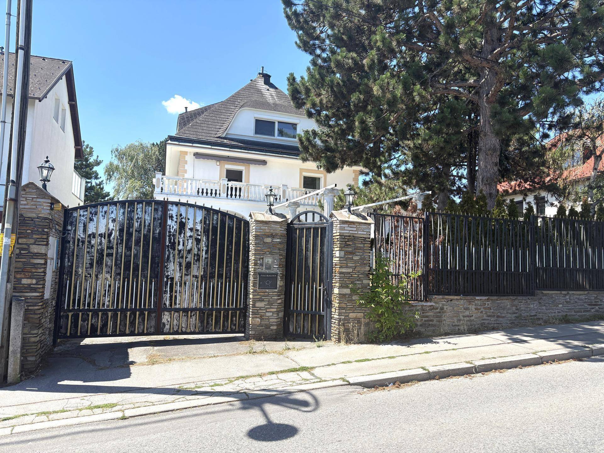 Repräsentatives Eingangstor aus Schmiedeeisen mit Blick auf die Villa im Hintergrund.