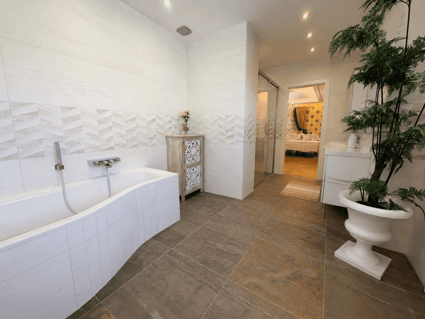 Geräumiges Badezimmer mit moderner Badewanne, Fliesenboden und direktem Zugang zum Schlafzimmer, bietet Komfort und Stil.