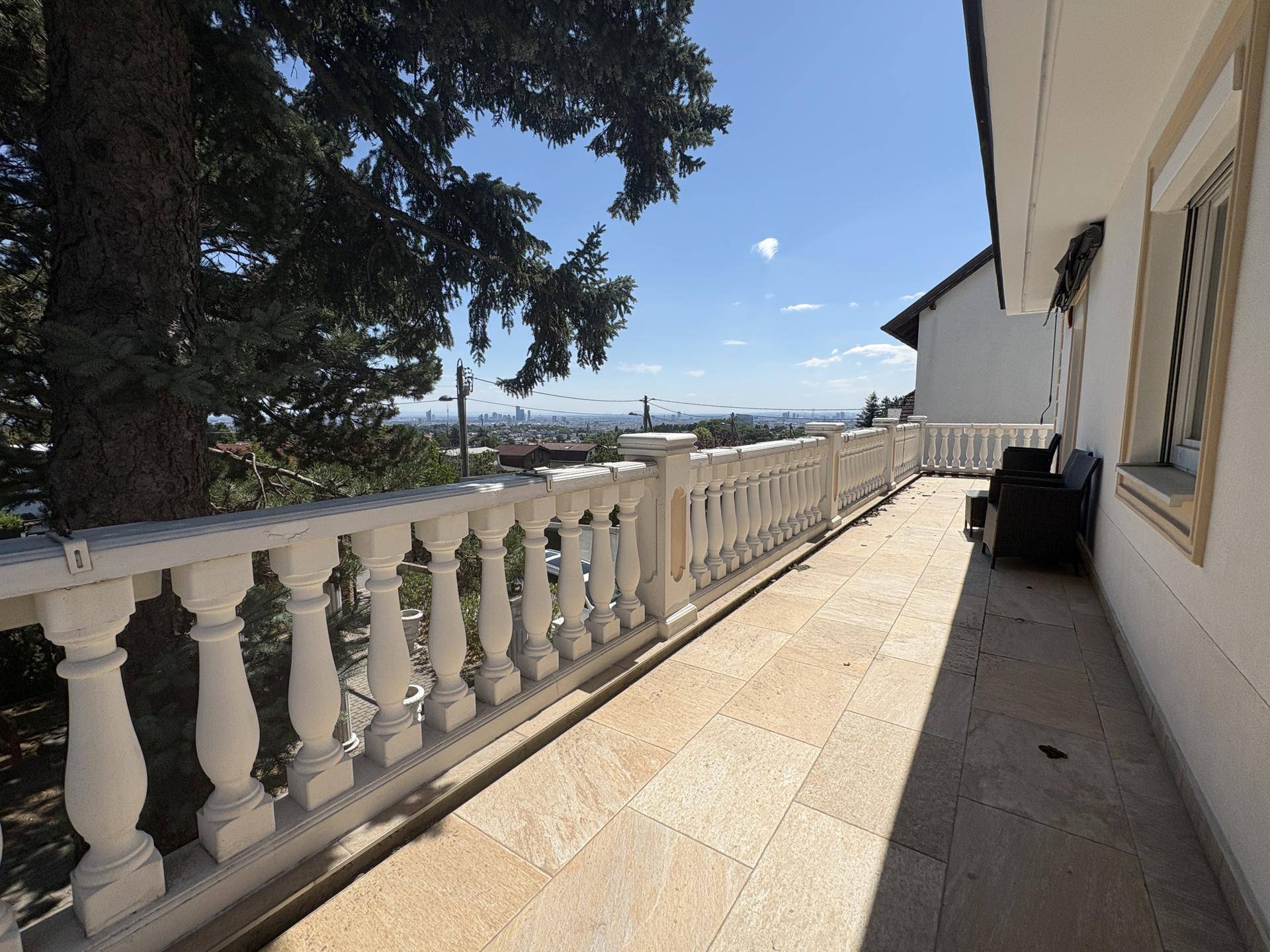 Geräumiger Balkon mit Fliesenboden und klassischem Geländer, bietet einen weiten Blick über die Stadt und die Umgebung.