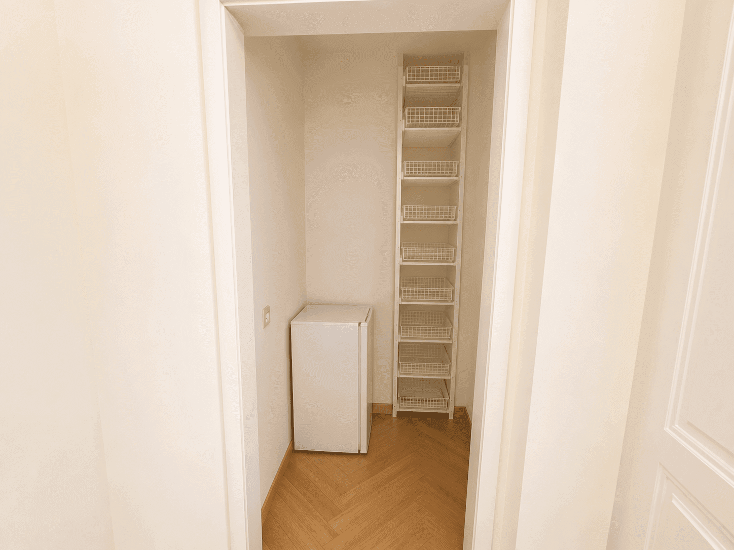 Praktischer Abstellraum mit kleinem Kühlschrank und Regalsystem, bietet zusätzlichen Stauraum.