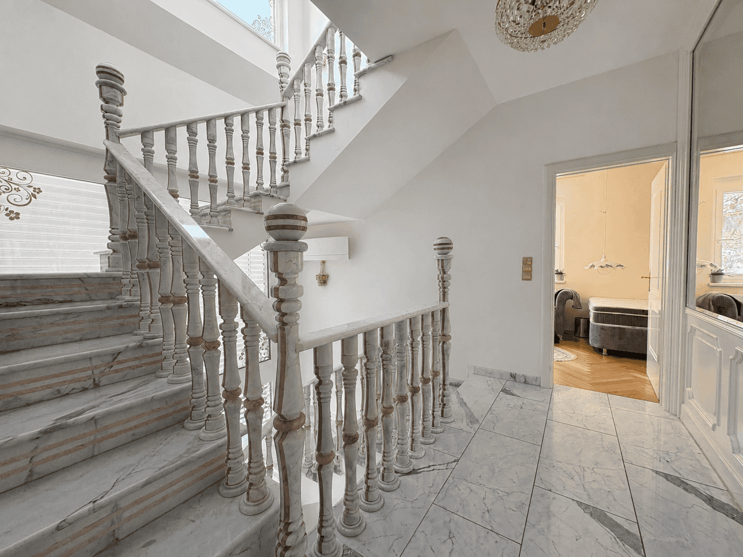 Elegantes Treppenhaus mit Marmorstufen und Geländer, das zu den oberen Etagen führt und einen luxuriösen Eingangsbereich schafft.