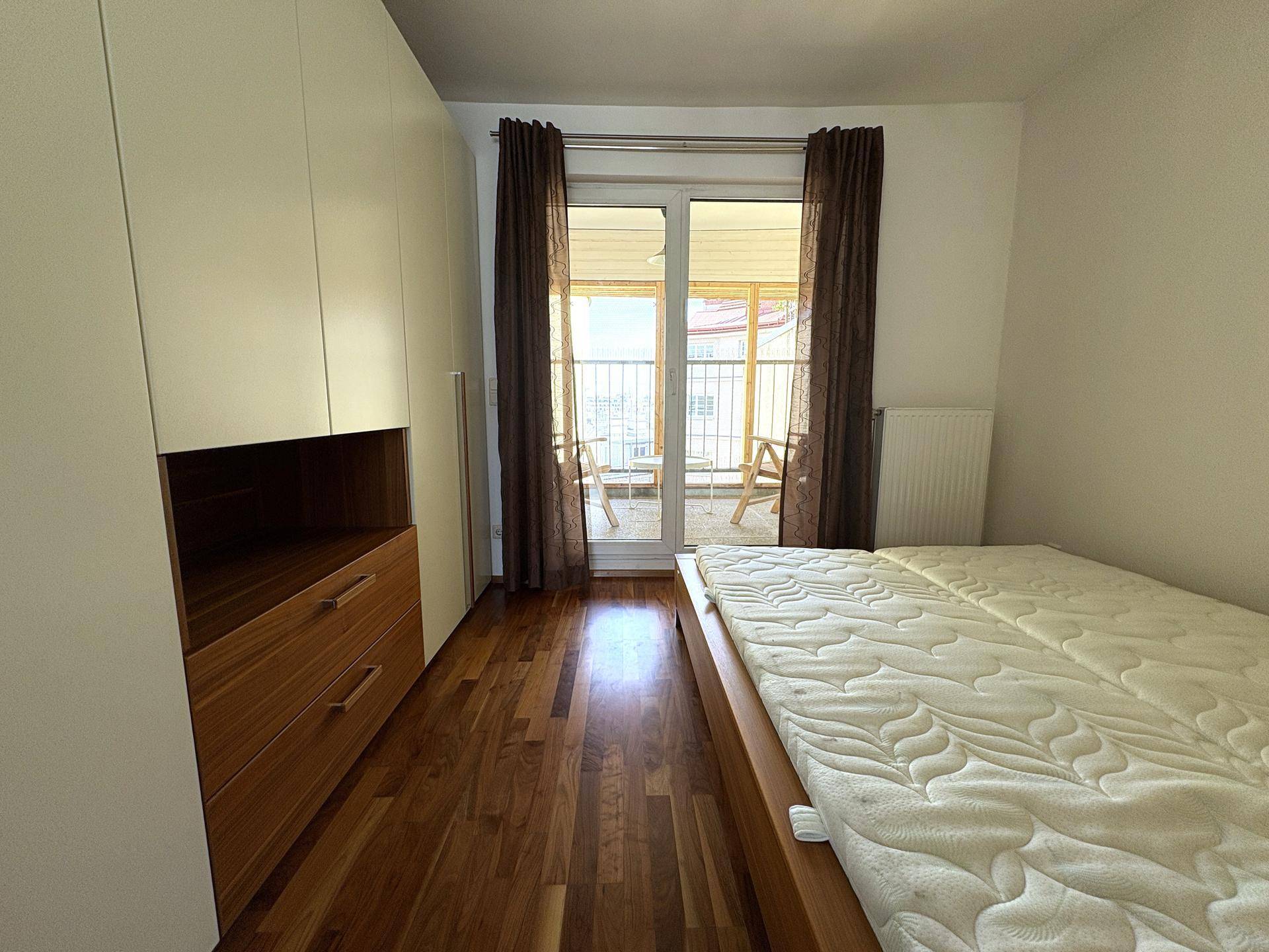 Schlafzimmer mit Holzboden, Einbauschränken und direktem Zugang zum Balkon, hell und geräumig.
