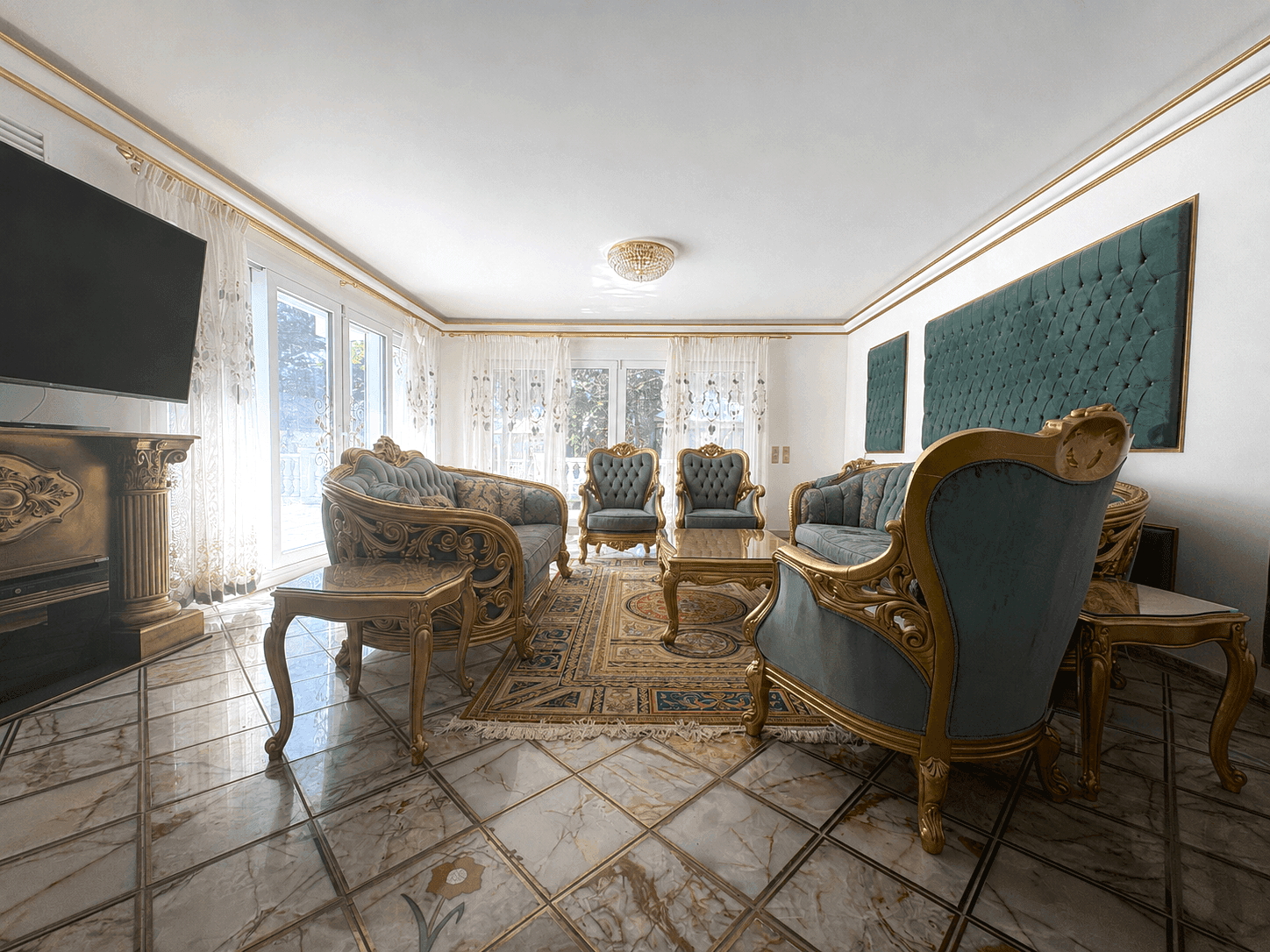 Luxuriöser Wohnbereich mit klassischem Mobiliar, großem Fernseher und Zugang zum Balkon.
