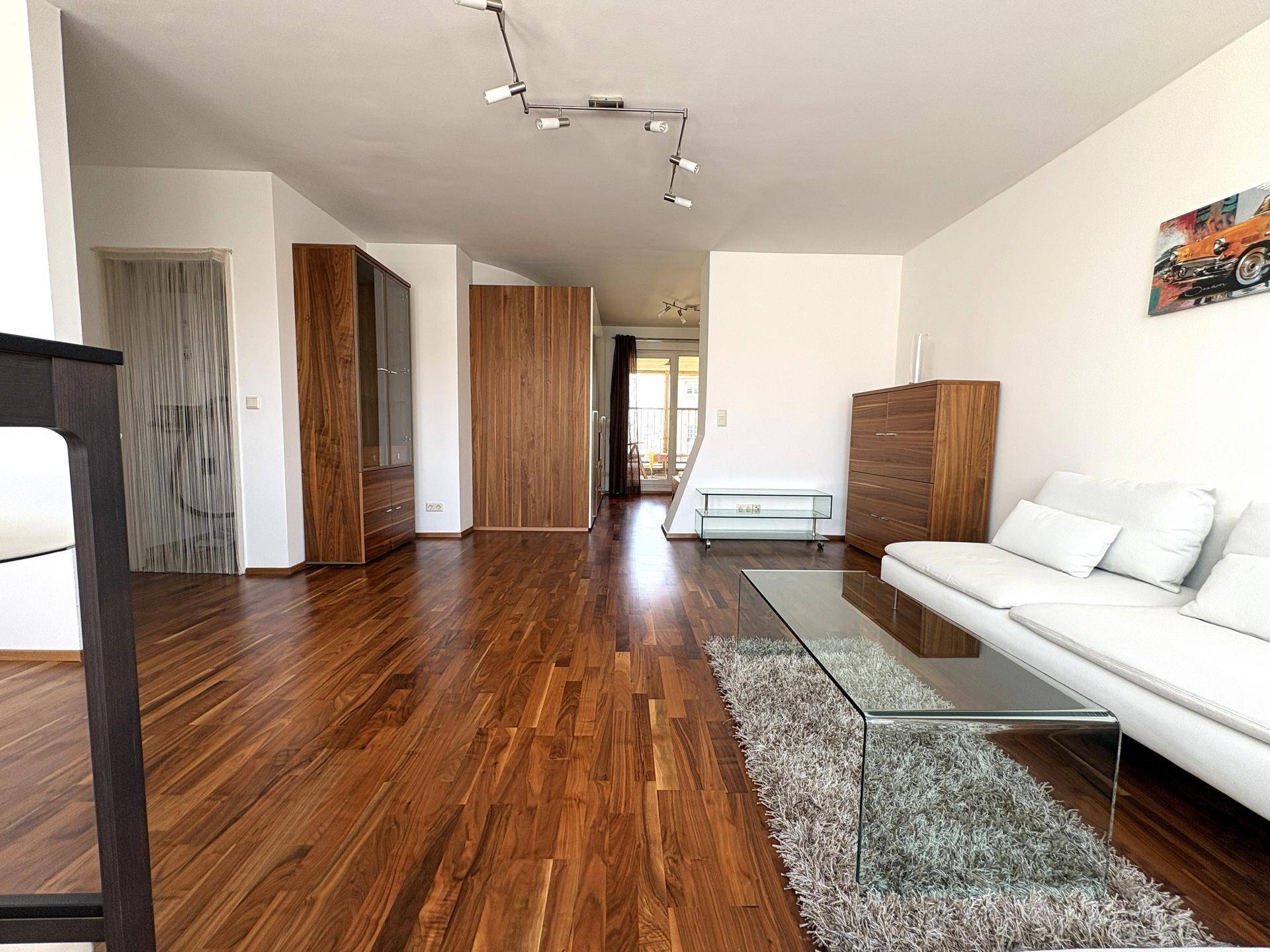 Heller Wohnbereich mit Holzboden und Blick in den Flur, ausgestattet mit modernen Möbeln und Dekoration.