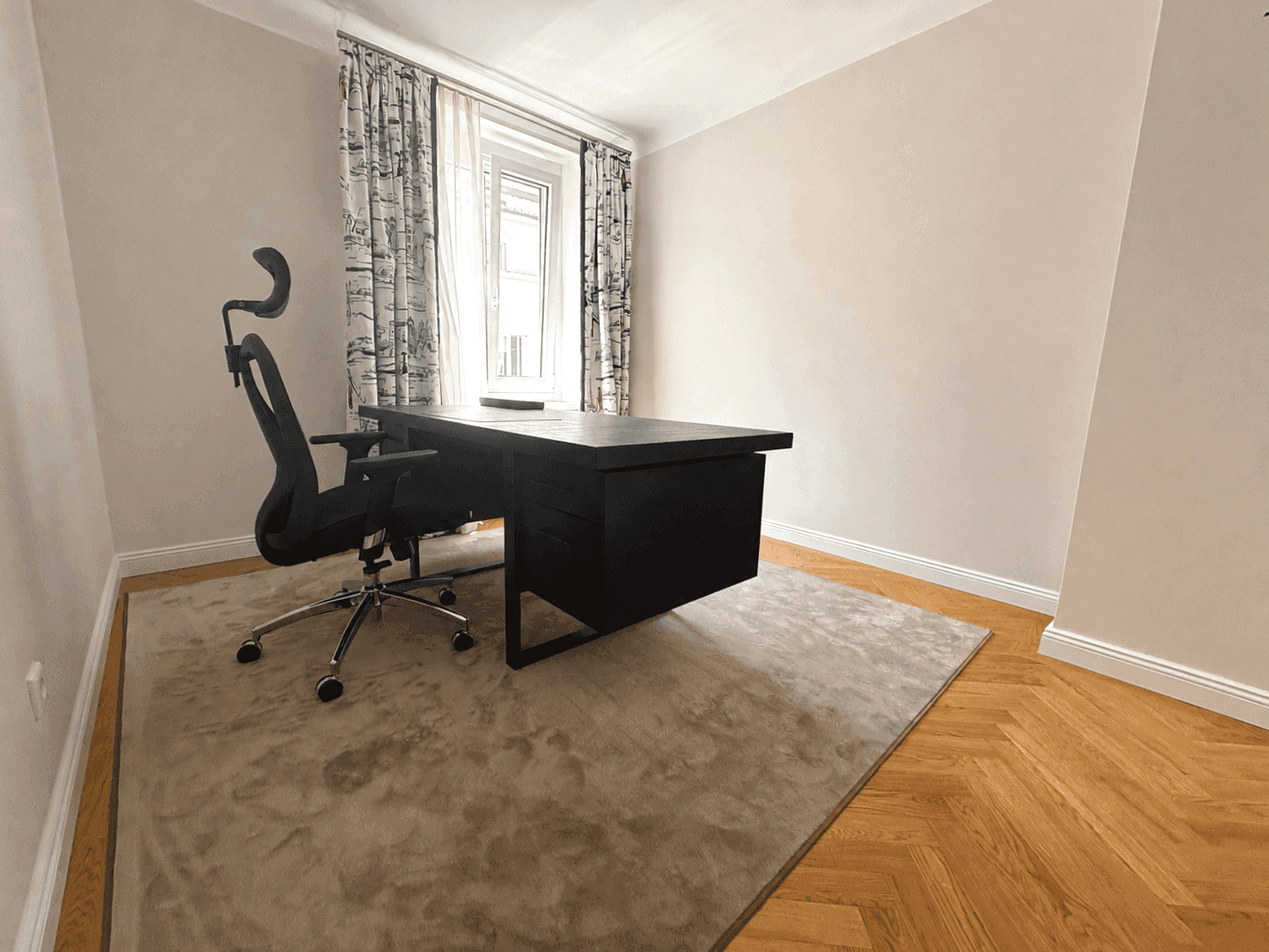 Helles Arbeitszimmer mit modernem Schreibtisch, Bürostuhl und Fenster mit gemusterten Vorhängen.