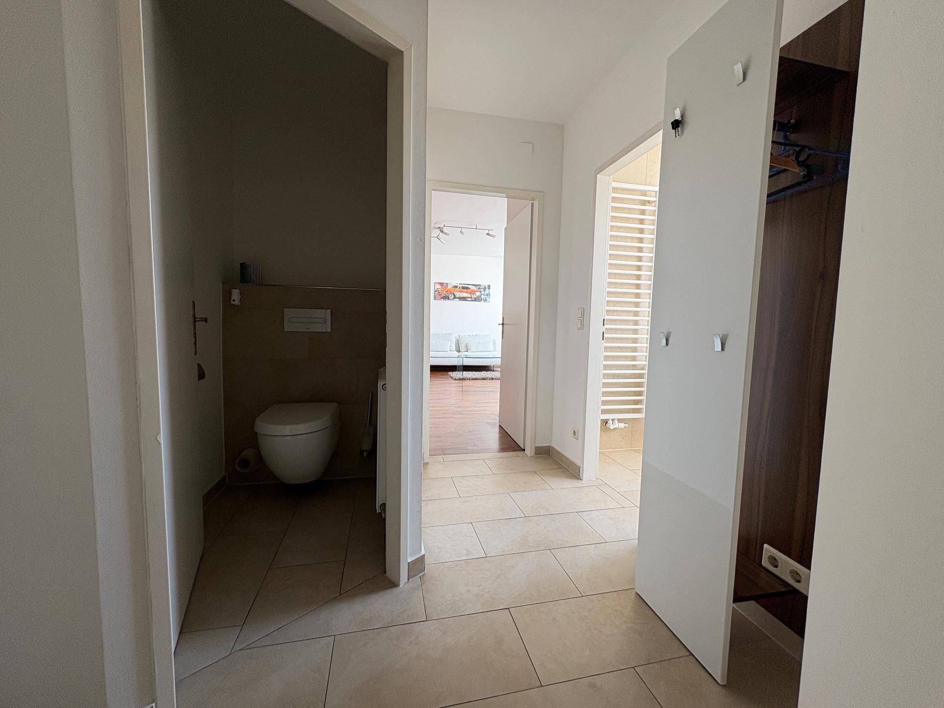 Heller Flur mit Fliesenboden und Zugang zu einem separaten WC, gut beleuchtet.