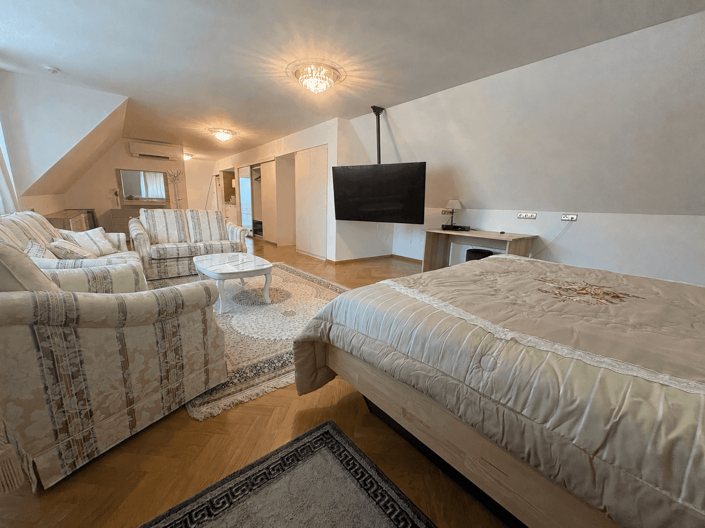 Helles Dachgeschoss-Schlafzimmer mit bequemen Sofas, großem Bett und Fernseher, perfekt für Entspannung.