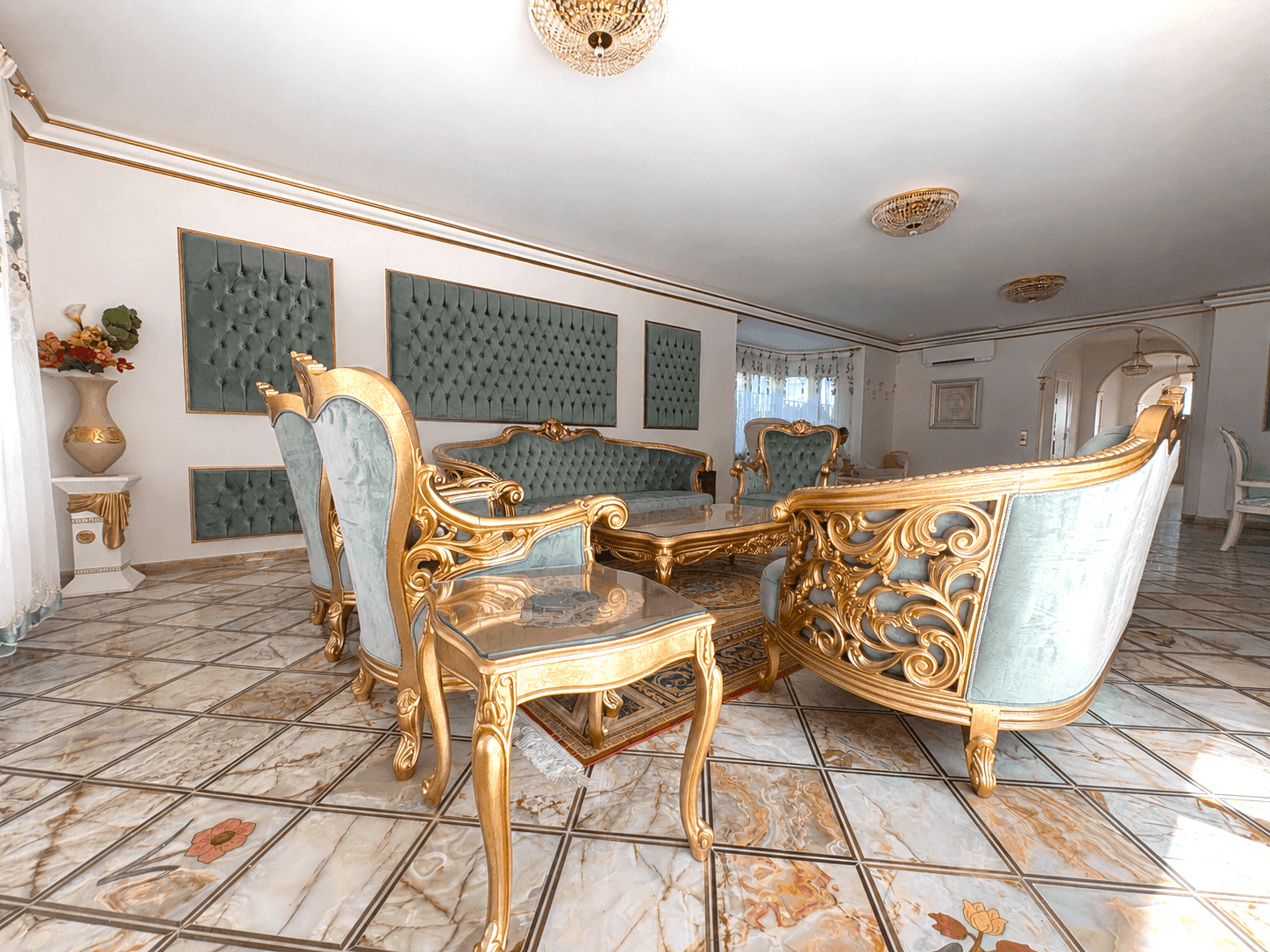 Opulenter Wohnbereich mit vergoldeten Möbeln und gemusterten Fliesen, ideal für Empfänge.