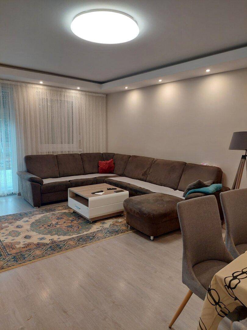 Geräumiger Wohnbereich mit großem Ecksofa, Teppich und hellem Laminatboden.