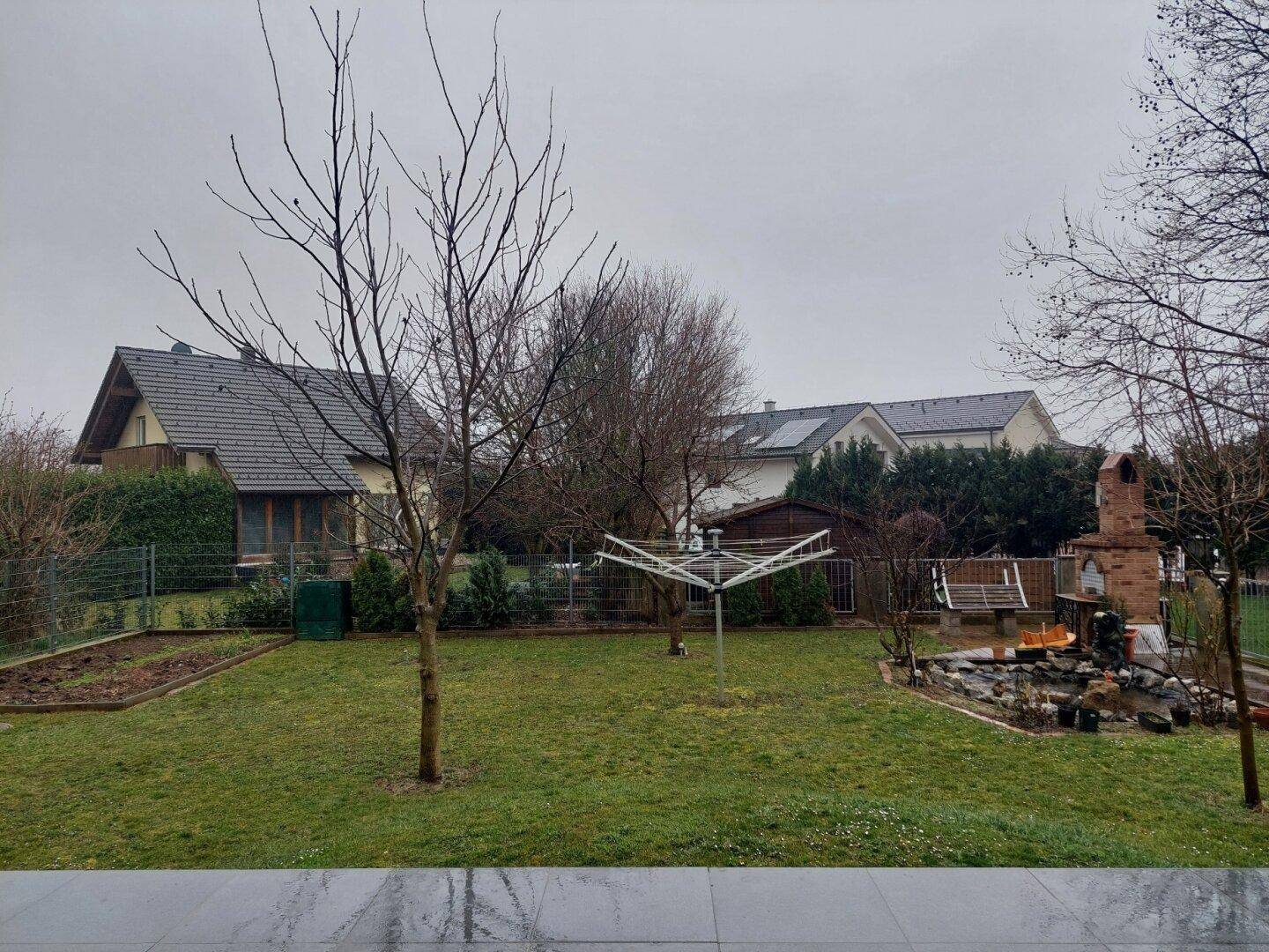 Weitläufiger Garten mit Rasen, Wäschespinne und angrenzenden Wohnhäusern in ländlicher Umgebung.