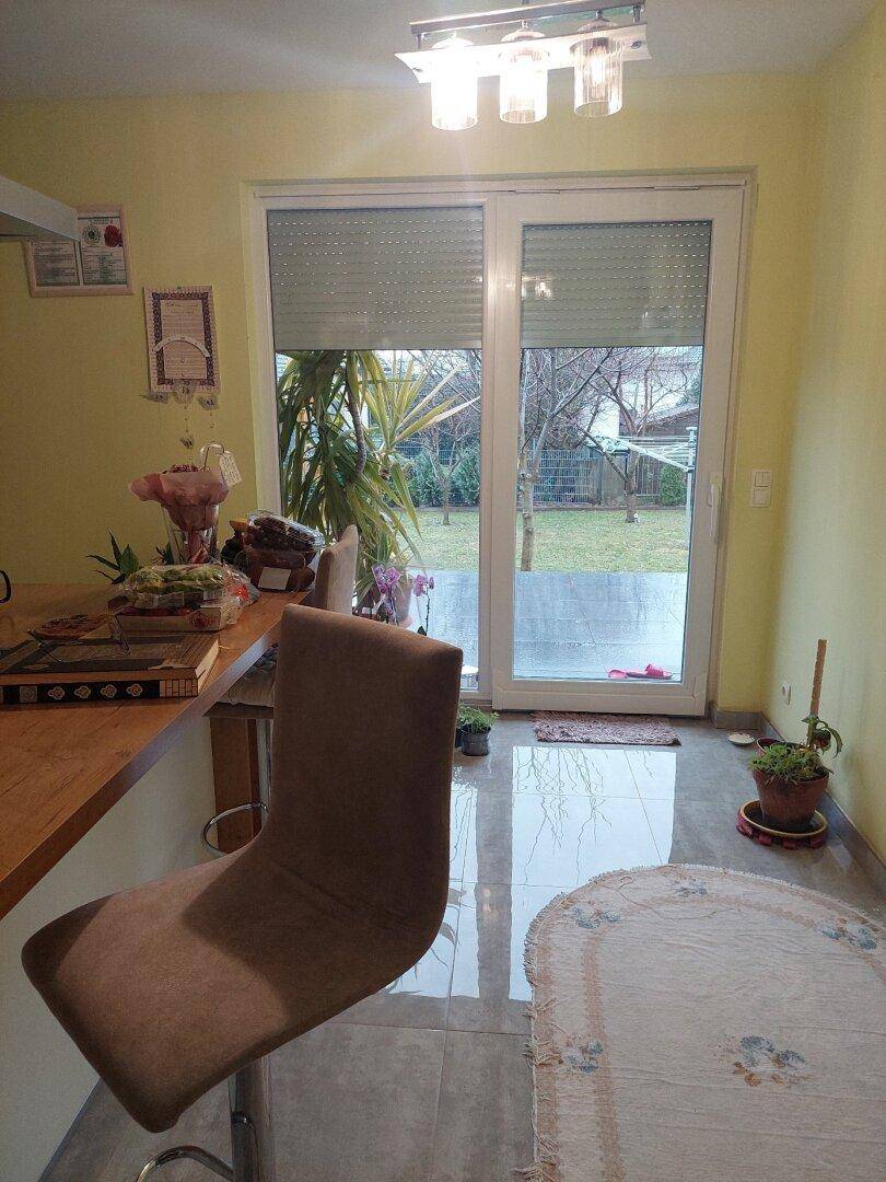 Küchenbereich mit Terrassenzugang, Barhocker und Blick auf den grünen Garten.