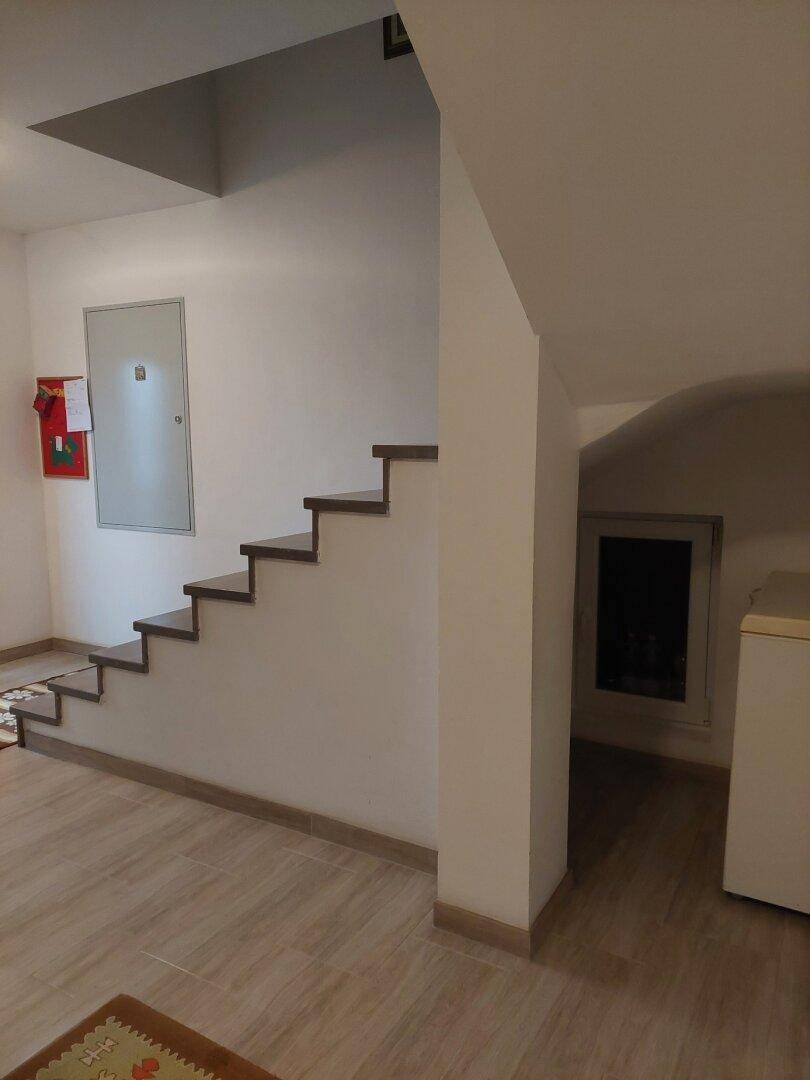 Heller Treppenaufgang mit Holzstufen und Zugang zu einem weiteren Bereich.