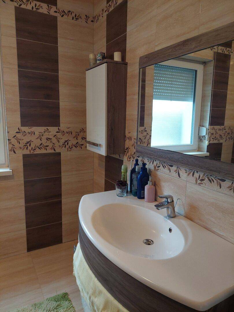Modernes Badezimmer mit Waschbecken, Spiegel und gemusterten Fliesen.