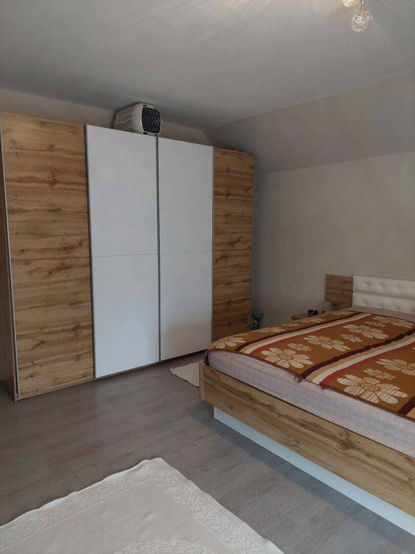 Schlafzimmer mit Doppelbett, großem Kleiderschrank und Dachschräge.