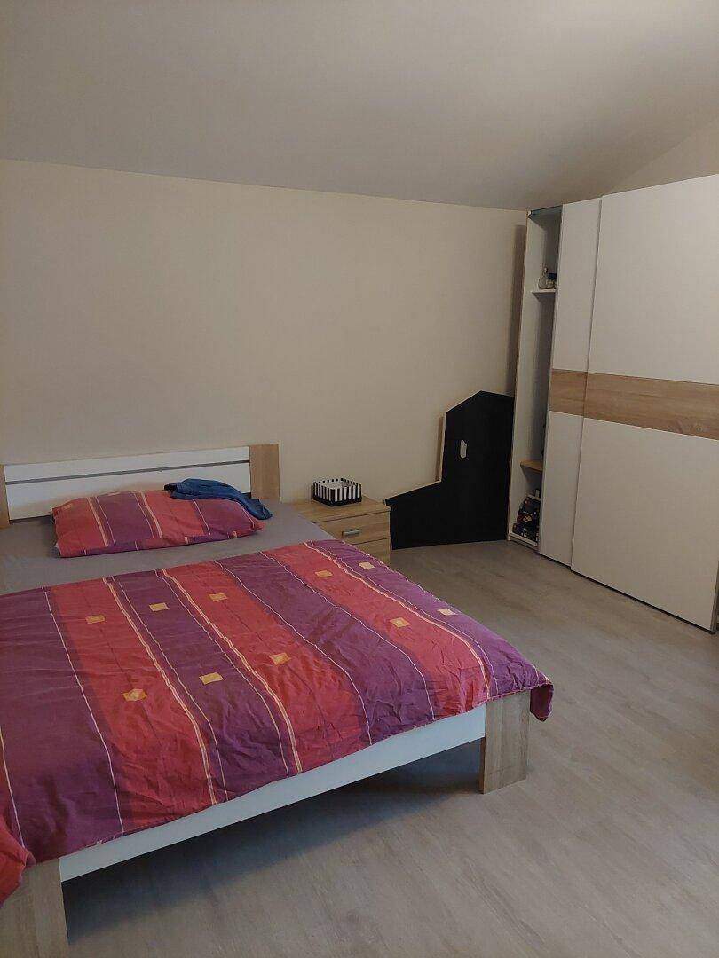 Schlafzimmer mit Doppelbett, Nachttisch und Kleiderschrank unter der Dachschräge.