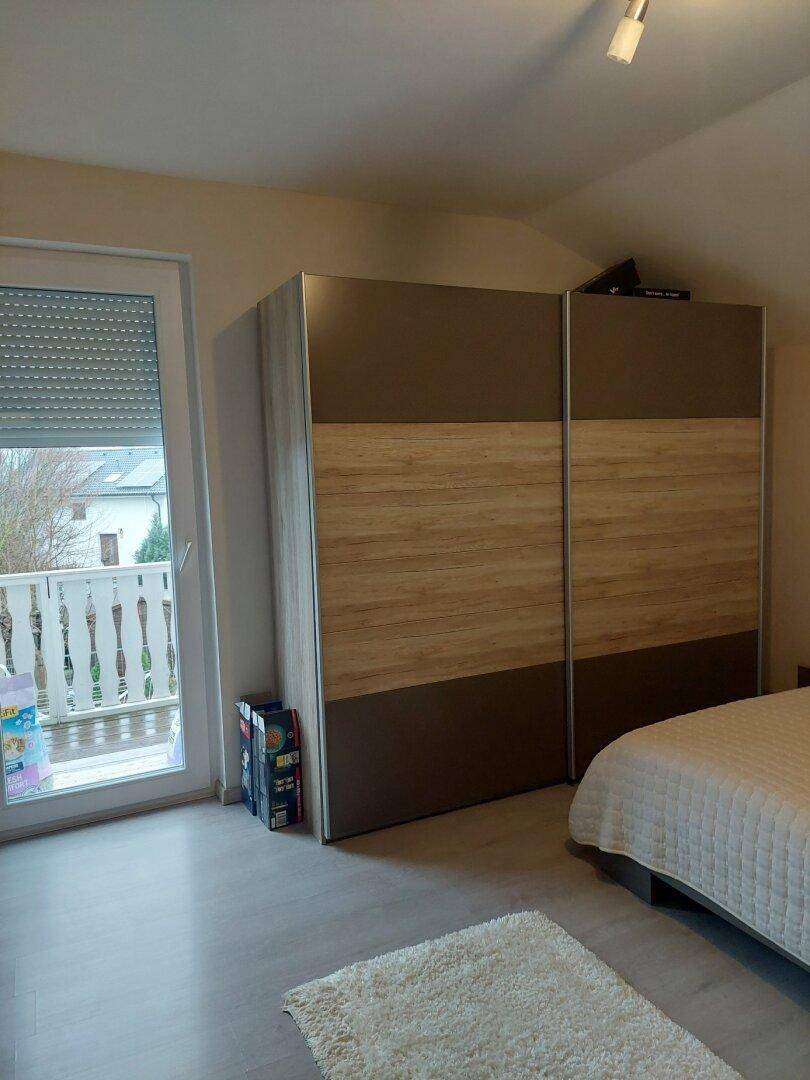 Schlafzimmer mit Kleiderschrank und Zugang zu einem französischen Balkon.
