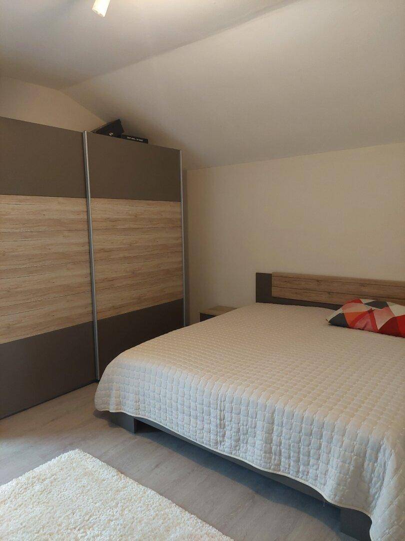Schlafzimmer mit Doppelbett, Kleiderschrank und hellem Teppich.