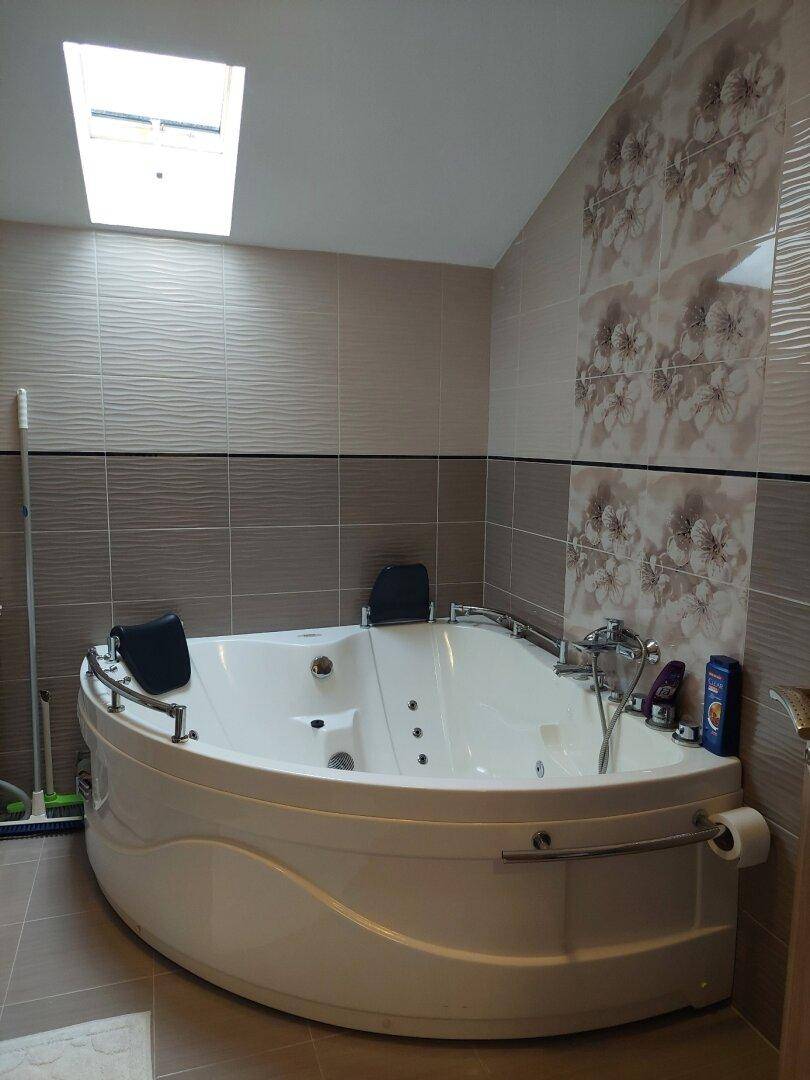 Geräumiges Badezimmer mit Whirlpool-Badewanne, Dachfenster und modernen Fliesen.