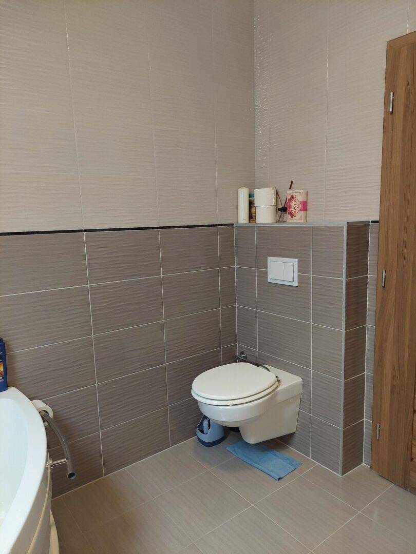 Modern gefliestes Badezimmer mit wandhängendem WC und hellen Wandfliesen.