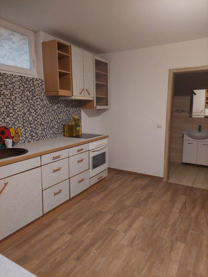 Funktionale Küche mit hellen Schränken, Mosaikfliesen und Laminatboden.