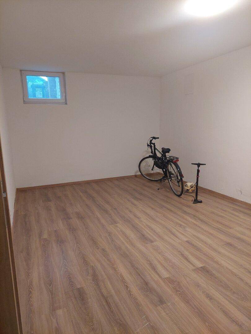 Raum mit Laminatboden, Fahrrad und Fahrradpumpe, ideal als Abstellraum oder Hobbyraum.
