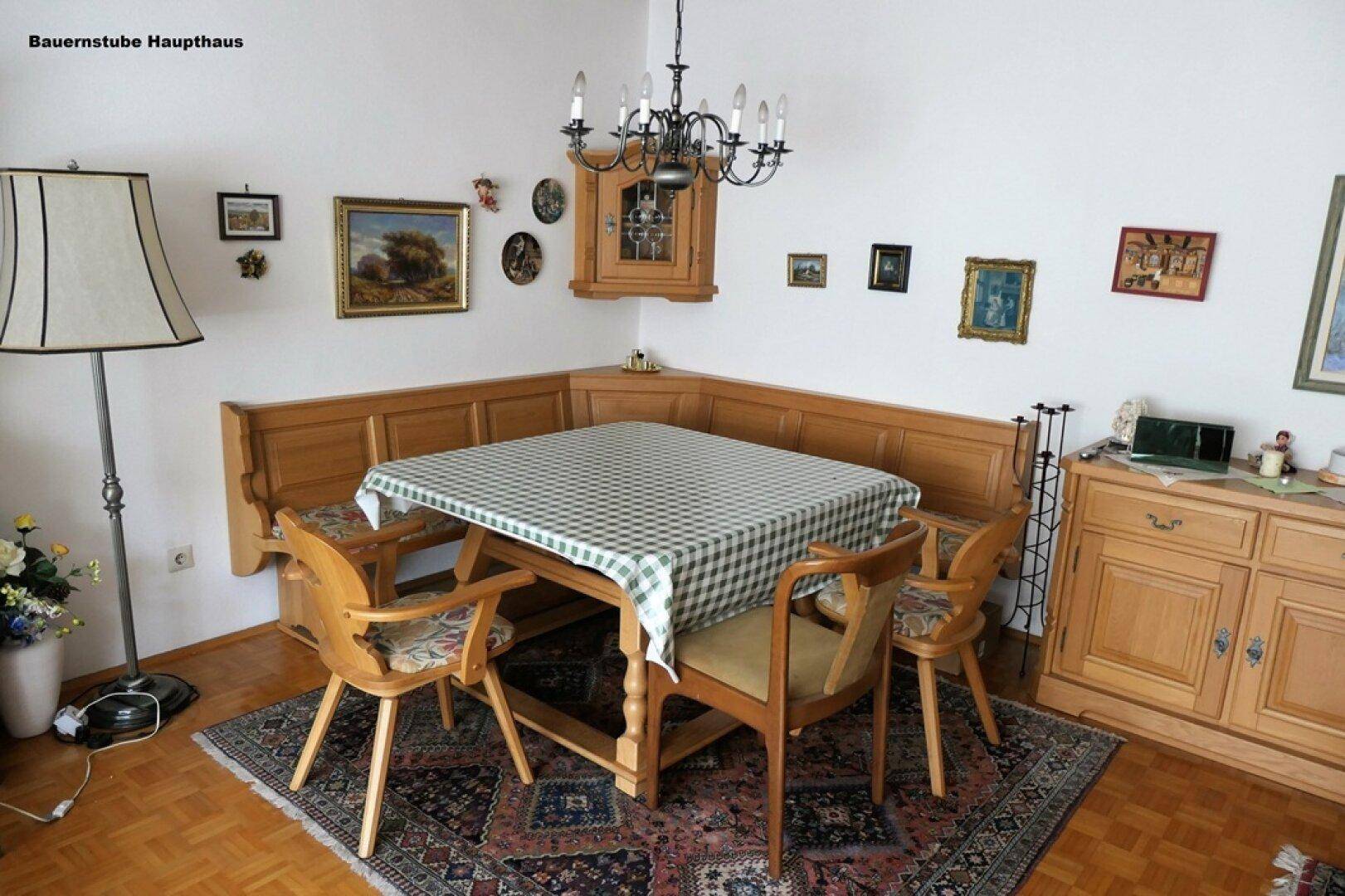 Rustikaler Essbereich mit Eckbank, Holztisch und Stühlen, beleuchtet von einem traditionellen Kronleuchter.