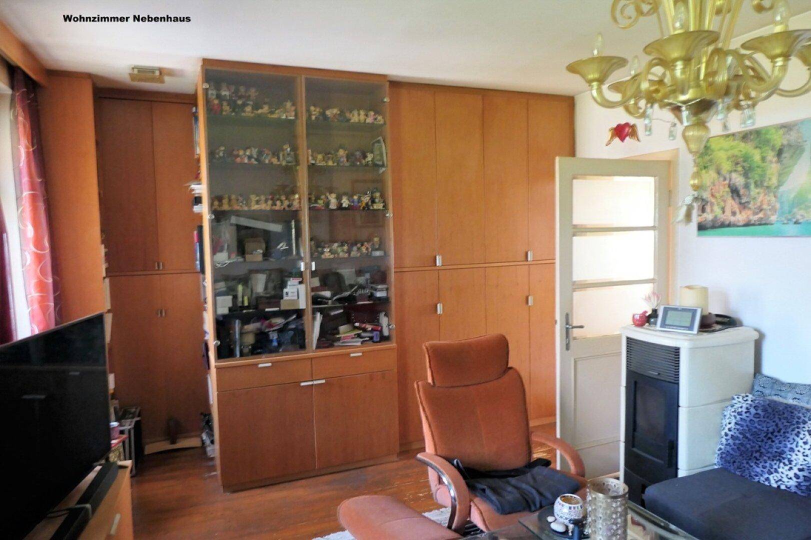Wohnzimmer mit umfangreichen Holzschränken, Vitrine und einem Kaminofen, bietet viel Stauraum.