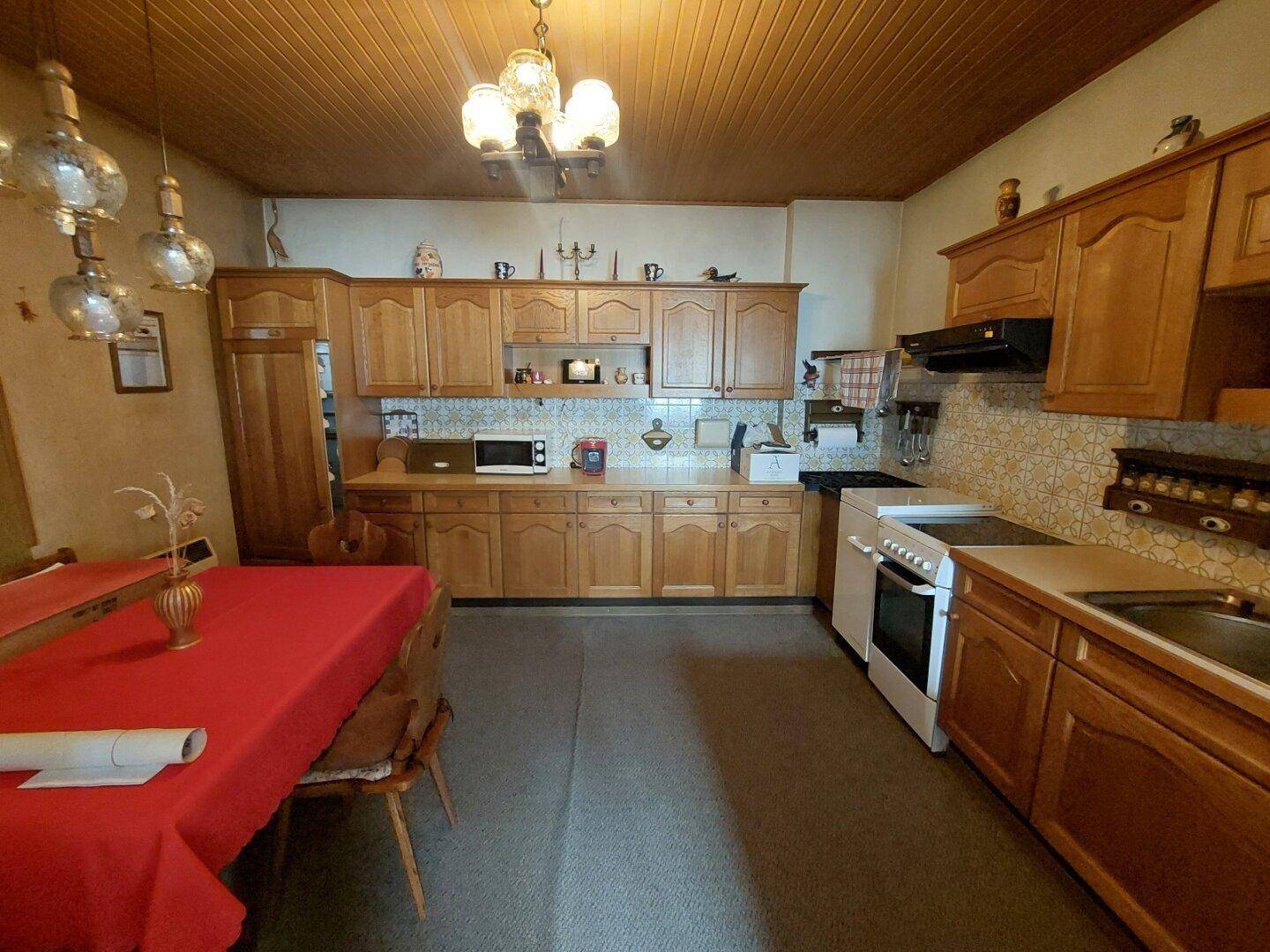 Geräumige Küche mit Holzschränken, traditionellen Fliesen und einem Esstisch.