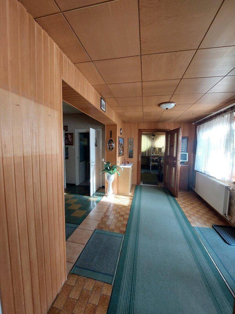 Gang mit Holzverkleidung an Wänden und Decke, sowie einem Fenster für natürliches Licht.
