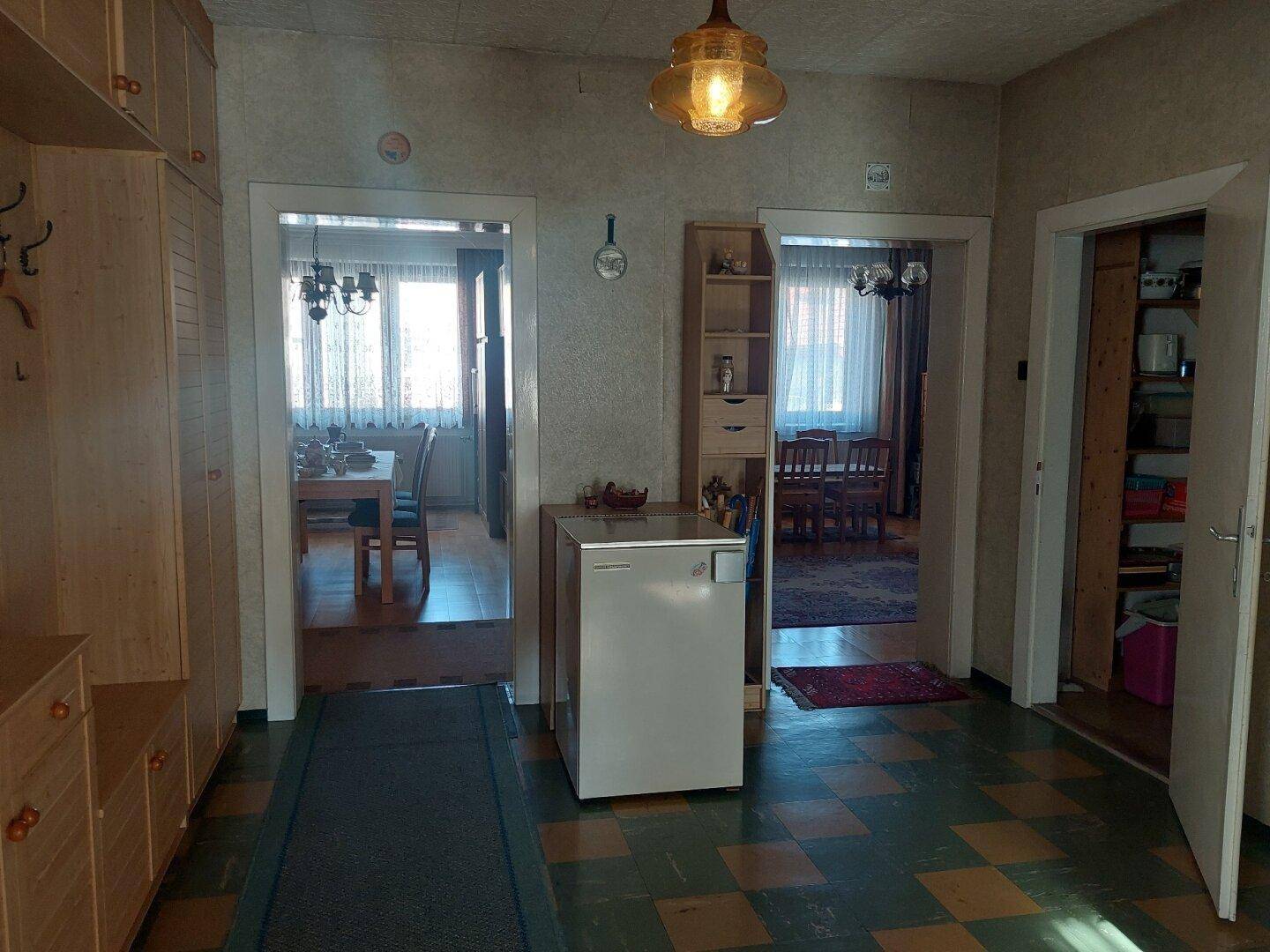 Flur mit mehreren Türen, die zu verschiedenen Räumen führen, und einem kleinen Kühlschrank.