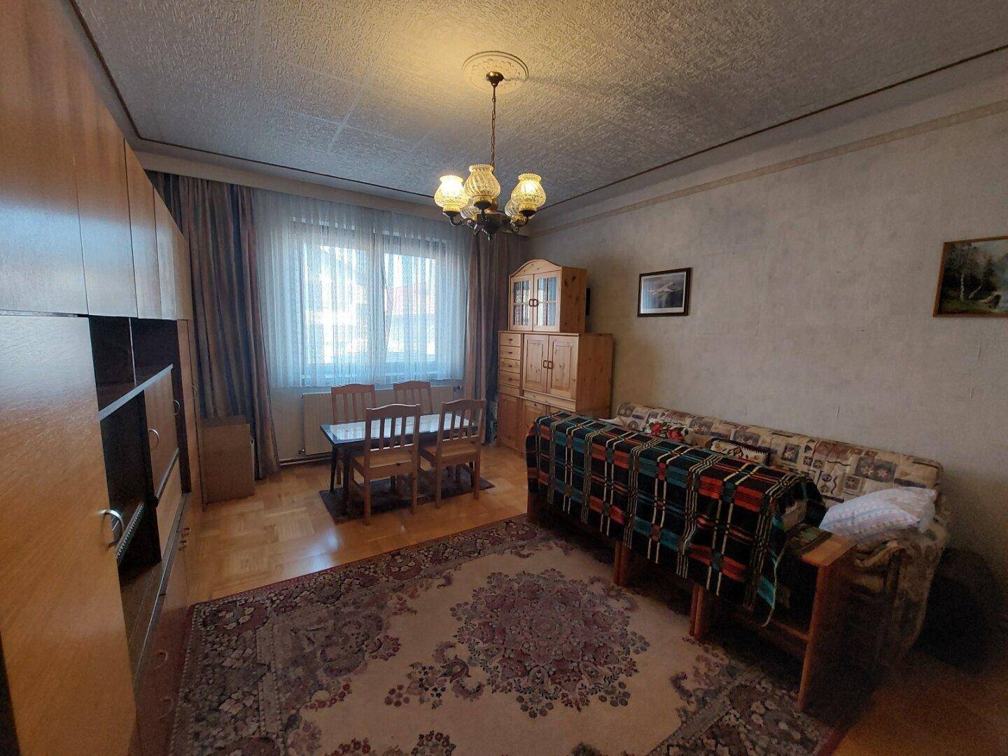 Wohn- und Essbereich mit traditionellen Möbeln, Teppich und einem Fenster.