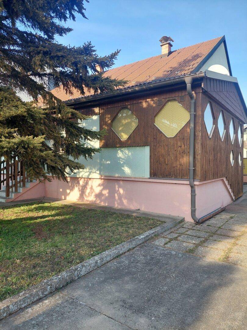 Seitenansicht des Hauses mit markanter Holzverkleidung und rautenförmigen Fenstern.