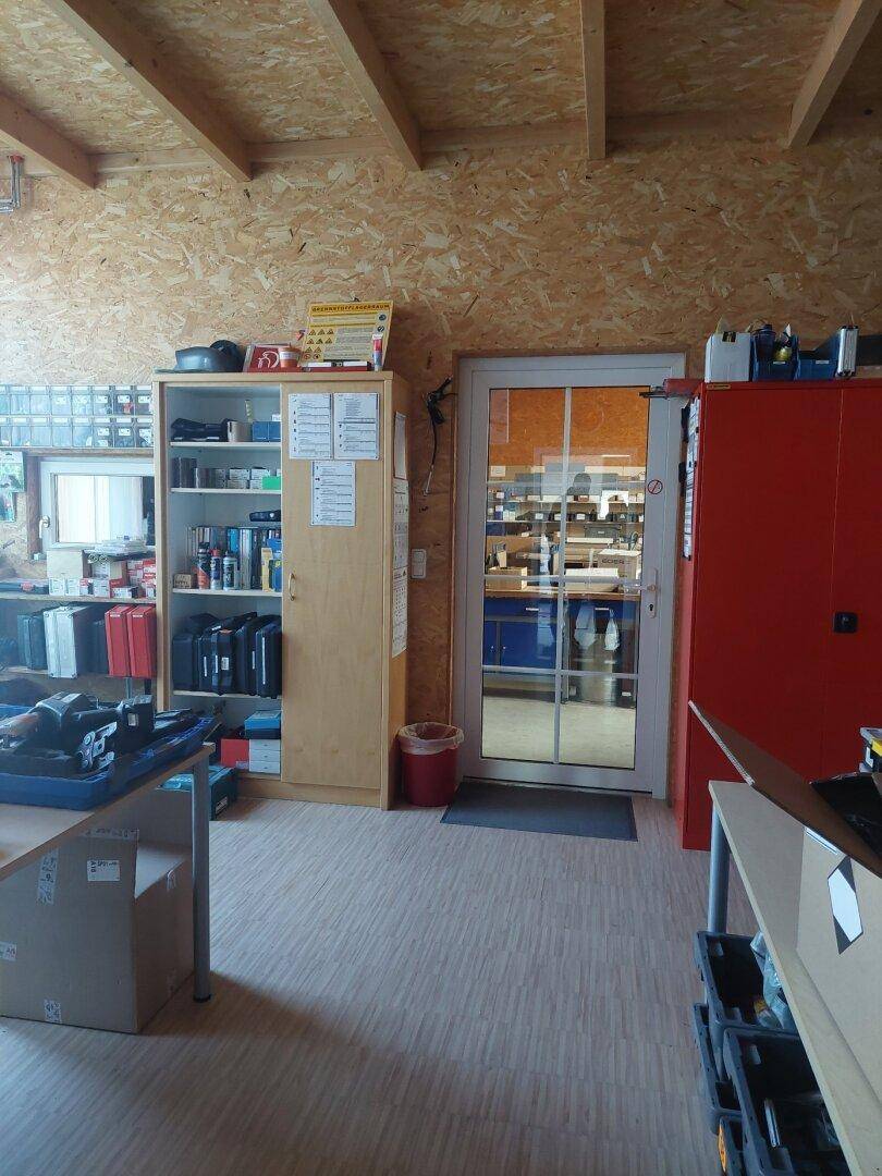 Arbeitsbereich mit Regalen, Schreibtisch und Holzverkleidung, bietet ausreichend Stauraum und eine praktische Arbeitsfläche.