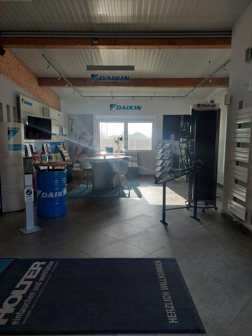 Heller Ausstellungsraum mit Produktpräsentationen, Fliesenboden und großen Fenstern, einladend und modern gestaltet.