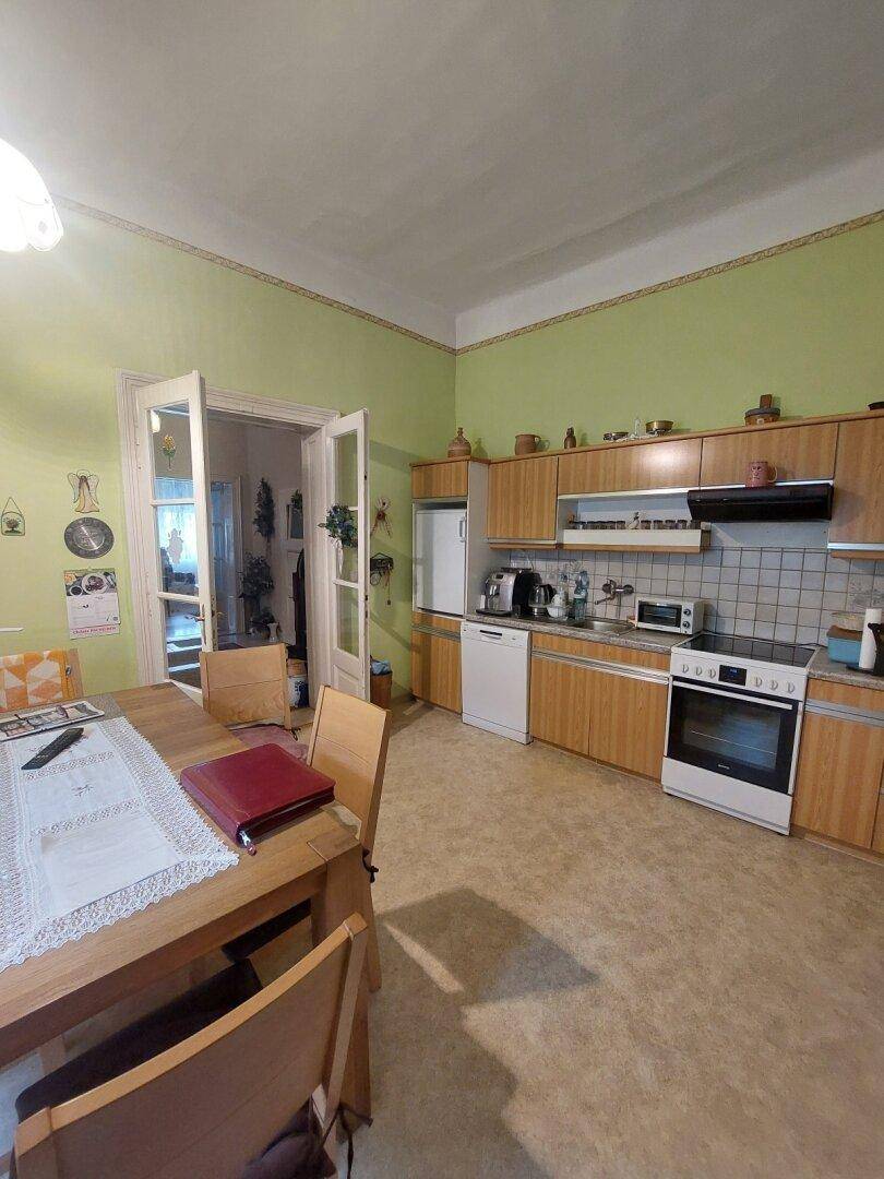 Geräumige Wohnküche mit Holzschränken, Esstisch und Blick auf den Essbereich.
